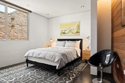 a bedroom with a bed and a black chair at Venice Rooftop 5bd 4 bt steps from the beach in Los Angeles