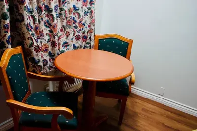 a wooden table and two chairs with a wooden table and a curtain at Red Carpet Motel By Ontario in Ontario