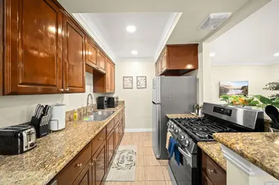 a kitchen with wooden cabinets and a stainless steel refrigerator at Elegant Exclusive Escape In Downtown Los Angeles in Alhambra