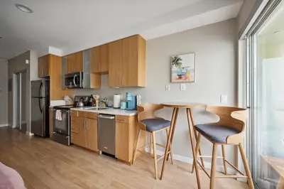 a kitchen with wooden cabinets and a table and chairs at Comfy studio near SM Promenade! Free parking! in Los Angeles