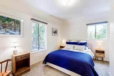 a bedroom with a blue bed and two windows at Natures Reserve in Lake Arrowhead