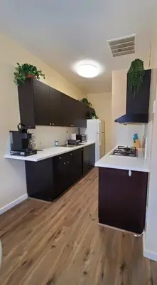 a kitchen with black cabinets and a wooden floor at Audrey Studio Apartment in Ktown in Los Angeles