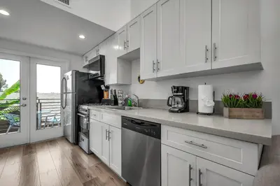 a kitchen with white cabinets and stainless steel appliances at Modern 1-Bedroom Loft in Hollywood with Parking, WiFi & Hollywood Sign View in Los Angeles