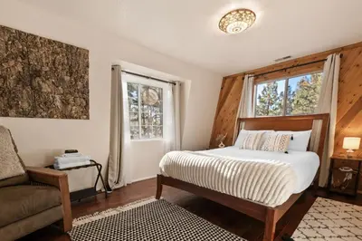 a bedroom with a bed and a chair and a window at Hillcrest HappyNest - Hot tub, fire pit, gas grill in Big Bear Lake