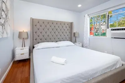 a white bedroom with a large bed and a window at Deluxe Modern 2BR Apt in Prime Location in Los Angeles