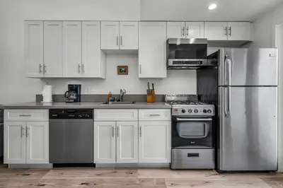 a kitchen with white cabinets and a stainless steel refrigerator at Stylish Modern one Bedroom Hollywood Loft With in unite washer dryer & Balcony in Los Angeles