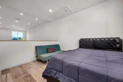 a bedroom with a large bed and a blue chair at 1-Bedroom Lofts in Hollywood Modern Design, Balcony, Parking & Hollywood Sign in Los Angeles