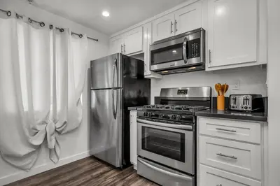 a kitchen with stainless steel appliances and white cabinets at Modern 2 Levels One-Bedroom Retreat in central Location in Hollywood in Los Angeles