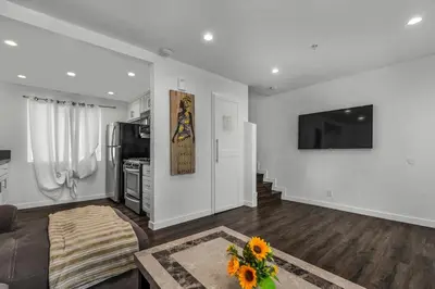 a living room with a couch and a tv on a wall at Modern 2 Levels One-Bedroom Retreat in central Location in Hollywood in Los Angeles