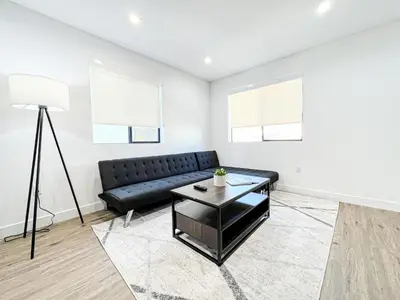 a living room with a black couch and a table at Elegant 4-Bedroom Family Home - Oak2 - LAD in Los Angeles