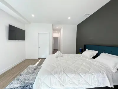 a bedroom with a large white bed with a blue headboard at Elegant 4-Bedroom Family Home - Oak2 - LAD in Los Angeles