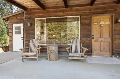 two chairs and a table on the porch of a cabin at Bear's Den @CN Lodge #5 in Ponderosa