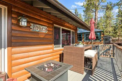 a cabin with a deck with a table and an umbrella at Little Lakeview Lodge in Big Bear Lake