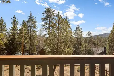 a wooden bench with a view of some trees at Little Lakeview Lodge in Big Bear Lake