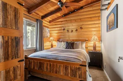 a bedroom with a bed in a log cabin at Little Lakeview Lodge in Big Bear Lake