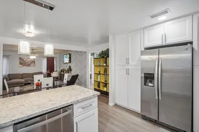 a kitchen with white cabinets and a stainless steel refrigerator at Cozy single story 2 bdrm family home near the BLVD in Lancaster