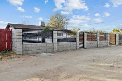 a house with a fence in front of it at Modern City Ranch 3 bdrm Family Home Access by Dirt Road in Palmdale