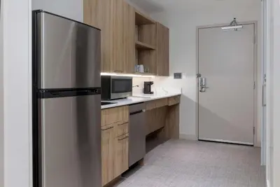 a kitchen with a stainless steel refrigerator and wooden cabinets at Homewood Suites by Hilton Cypress Orange County in Cypress