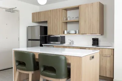 a kitchen with a counter and some green chairs at Homewood Suites by Hilton Cypress Orange County in Cypress