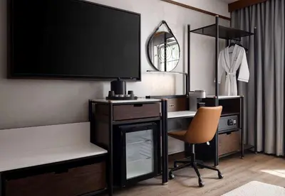 a room with a desk with a television and a chair at Sanctity Hotel Rancho Cucamonga, Tapestry Collection Hilton in Rancho Cucamonga