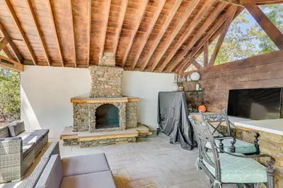 an outdoor living room with a stone fireplace at Lake Arrowhead Cabin with Hot Tub and Mountain Views! in Lake Arrowhead