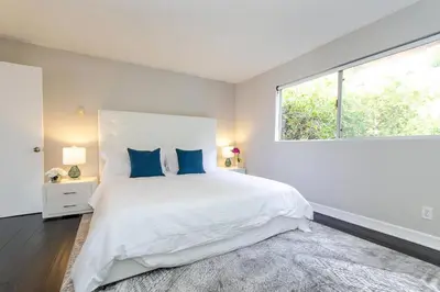 a white bedroom with a large bed with blue pillows at SURF-N-SAND 2-Bedrooms, MALIBU in Malibu
