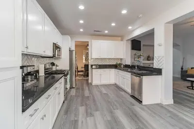 a kitchen with white cabinets and black counter tops at Modern 4BR Oasis, Fireplace, Patio & Spacious Family Room in Palmdale