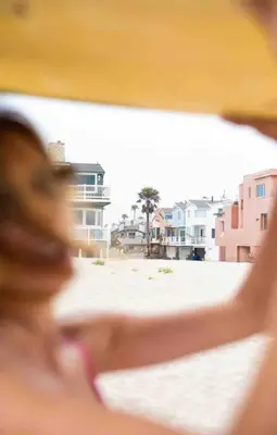 a woman standing on a beach with buildings in the background at Cool Cali Vibe - Barefoot Stepping Distance 2 Sand in Oxnard