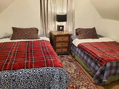 a bedroom with two beds and a night stand with a lamp at The Treetop Terrace at The Historic Arrowhead Lodge in Twin Peaks