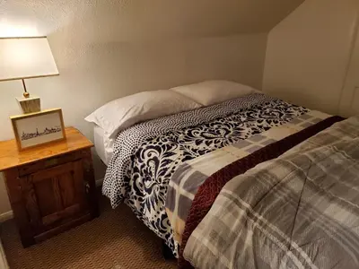 a bedroom with a bed and a table with a lamp at The Treetop Terrace at The Historic Arrowhead Lodge in Twin Peaks