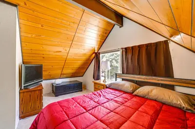 a bedroom with a red bed and a tv at Frazier Park Cabin with Ping-Pong Table, Near Trails in Frazier Park