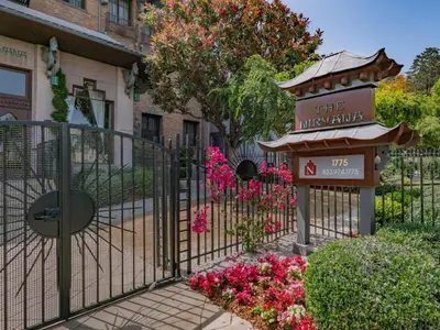 a gate with a sign and flowers in front of a building at The Nirvana Apartment Hotel in Los Angeles