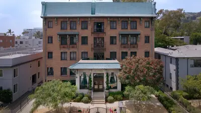 a large brick building with a porch in front of it at The Nirvana Apartment Hotel in Los Angeles