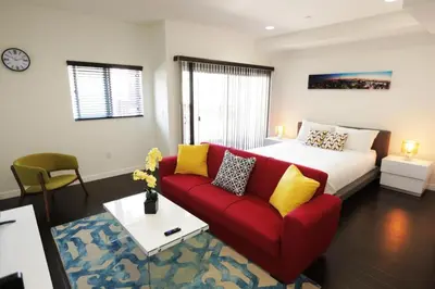 a living room with a red couch and a bed at Downtown Cosmopolitan Residences in Los Angeles