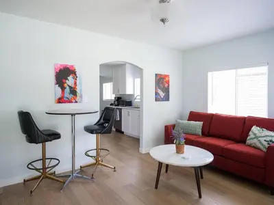 a living room with a red couch and a table at Family Renovated Home, Netflix, AC, WD, Putt Putt in Fullerton