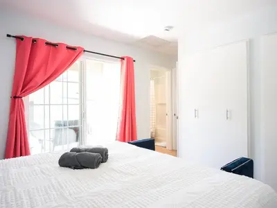 a bedroom with a large white bed with red curtains at Family Renovated Home, Netflix, AC, WD, Putt Putt in Fullerton