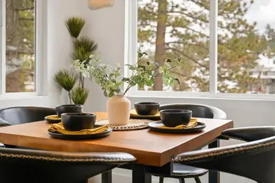 a wooden table with black chairs and a vase on it at Luxe Lakefront with Hot Tub, Fire Pit, Game Room, Boat Dock in Big Bear Lake