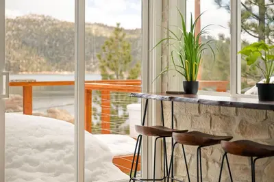 a room with a table and two stools in front of a window at Luxe Lakefront with Hot Tub, Fire Pit, Game Room, Boat Dock in Big Bear Lake