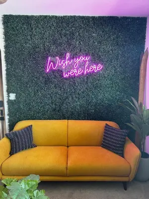 a yellow couch in front of a wall with a neon sign at Luxe Lakefront with Hot Tub, Fire Pit, Game Room, Boat Dock in Big Bear Lake