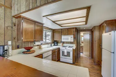 a kitchen with wooden cabinets and a white refrigerator at Chic Lake Arrowhead Retreat 4 Seasons of Fun! in Lake Arrowhead