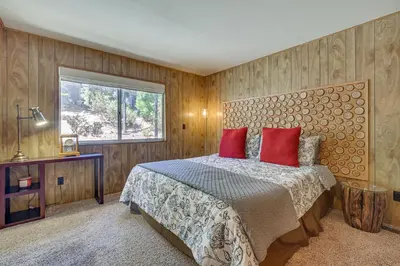 a bedroom with a bed with red pillows and a window at Chic Lake Arrowhead Retreat 4 Seasons of Fun! in Lake Arrowhead