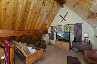 a living room with a tv and wooden ceiling at Lake Arrowhead Charming Chalet in Lake Arrowhead