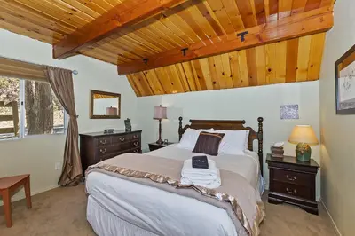 a bedroom with a large bed and wooden ceilings at Lake Arrowhead Charming Chalet in Lake Arrowhead