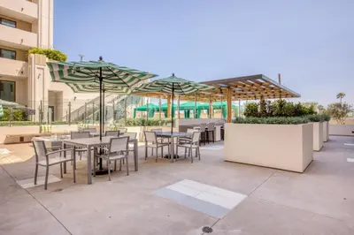 an outdoor patio with tables and chairs and umbrellas at Blueground Mid-Wilshire pool near The Grove LAX-1223 in Los Angeles