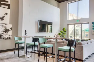 a living room with a bar with green chairs at Blueground Mid-Wilshire pool near The Grove LAX-1223 in Los Angeles