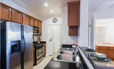 a kitchen with a stainless steel refrigerator and wooden cabinets at LALA House -1Br with Free Parking, Pool, Laundry in Los Angeles