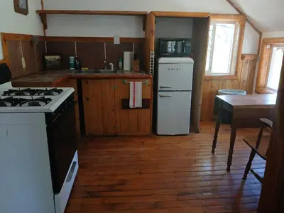 a kitchen with a stove and a refrigerator and a table at Big Bear Lake - Tulip Lane Cabin #22 in Big Bear Lake