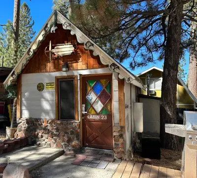 a small house with a wooden door and a tree at Big Bear Lake - Tulip Lane Cabin #23 - Micro Cabin in Big Bear Lake