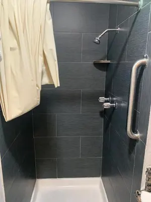 a bathroom with a shower with black tiles at Hi Rise Motel in Lynwood
