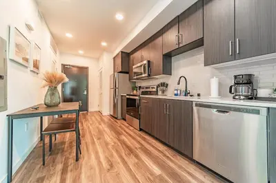 a kitchen with wooden cabinets and a table and a counter at Sunset Blvd Studio Apt in the Heart of Hollywood in Los Angeles
